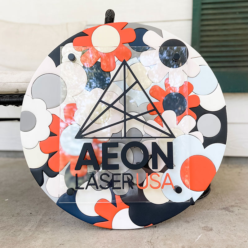 round wooden sign made of orange, blue, and white flowers with a prism and 成人短视频+app logo on top