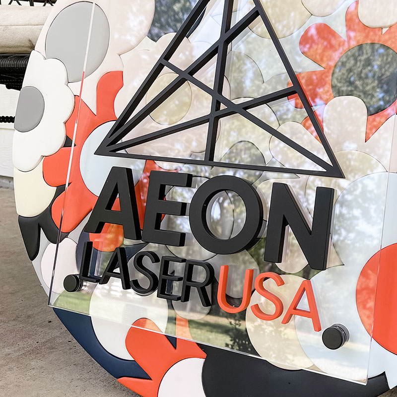 round wooden sign made of orange, blue, and white flowers with a prism and 成人短视频+app logo on top